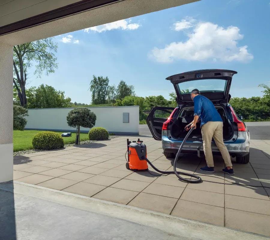 man cleaning boot of car with wet vaccum